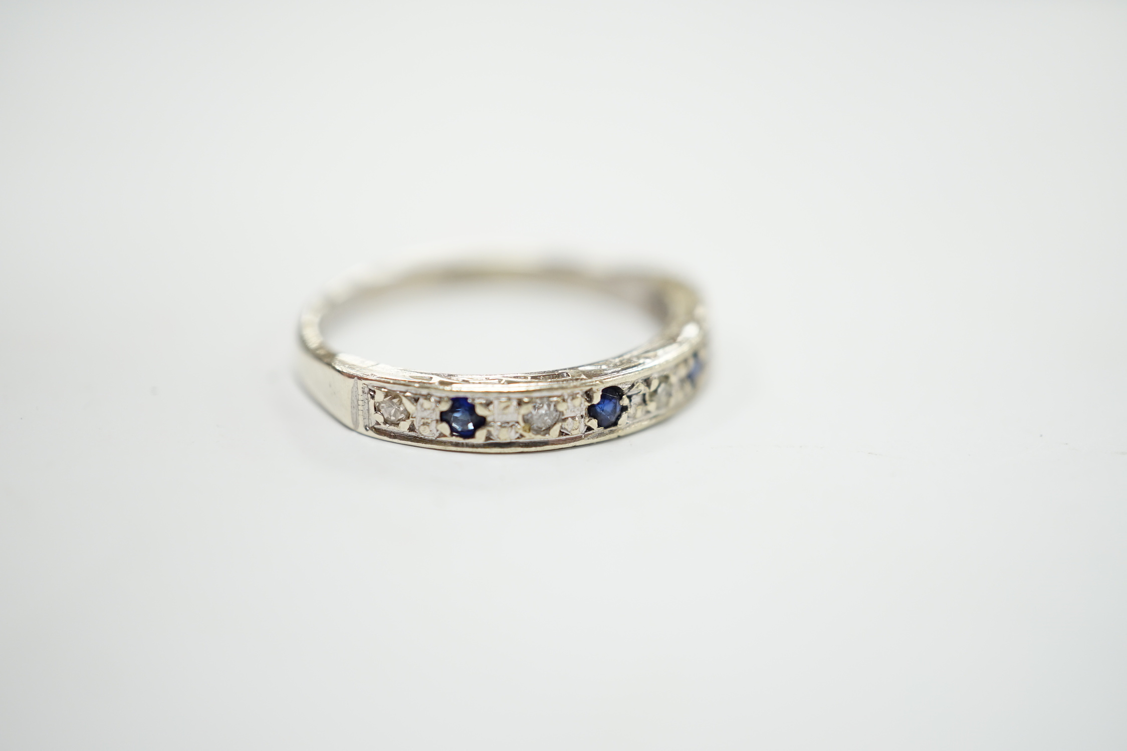 A modern 9ct white hold sapphire and diamond chip set half hoop ring, size N, gross weight 2.1 grams.